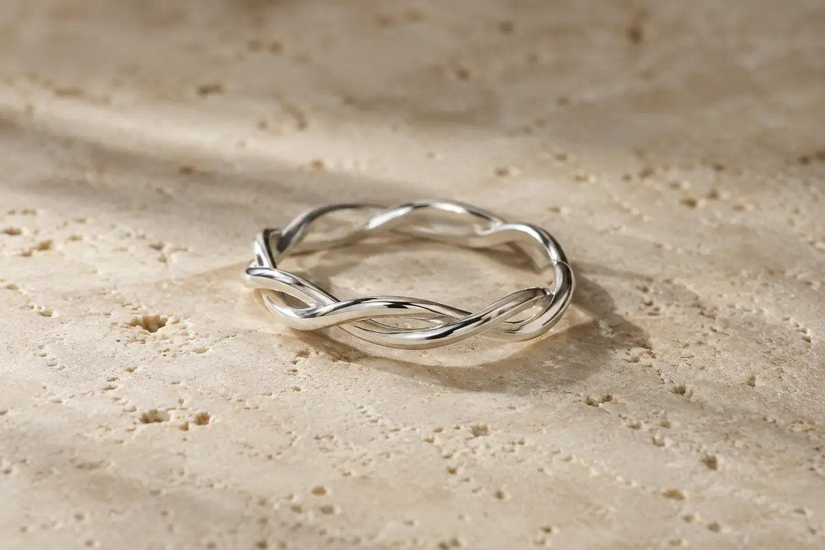 Bague fine en argent 925 posée sur du travertin clair, avec un motif torsadé inspiré de l’infini