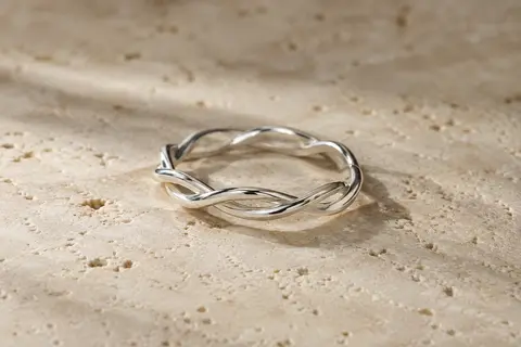 Bague fine en argent 925 posée sur du travertin clair, avec un motif torsadé inspiré de l’infini