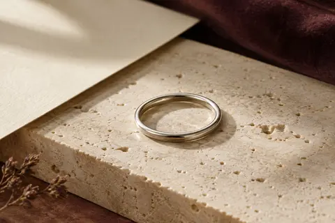 Bague fine et unie en argent sterling 925, finition polie, posée sur du travertin clair