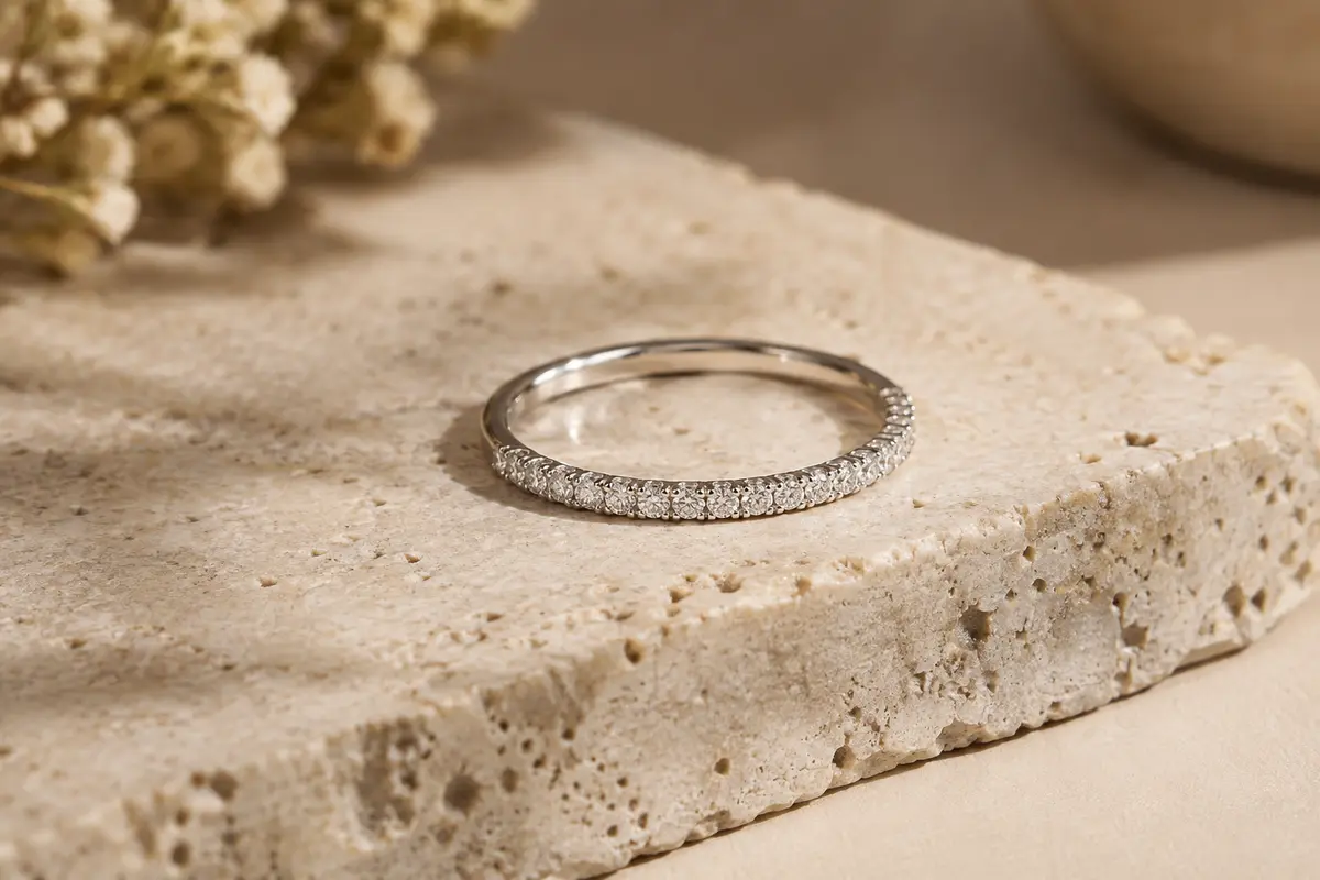Bague éternité fine en argent 925 sertie de zircon, posée sur du travertin clair