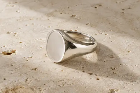 Chevalière ovale en argent posée sur du travertin clair, avec un anneau de 4 mm.