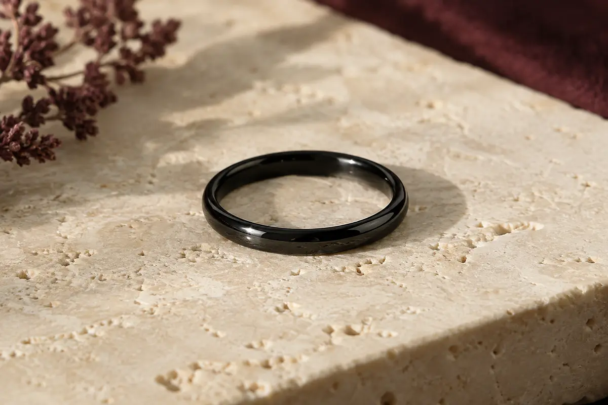 Bague fine noire brillante en acier inoxydable posée sur du travertin clair