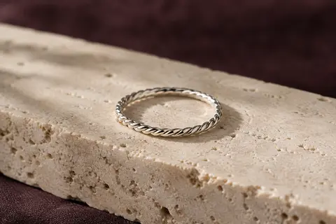 Bague fine en argent sterling à motif de corde torsadée, posée sur du travertin clair