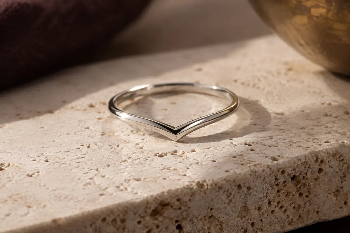 Bague fine en argent 925 au profil chevron, posée sur du travertin clair dans une lumière douce