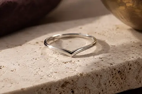 Bague fine en argent 925 au profil chevron, posée sur du travertin clair dans une lumière douce